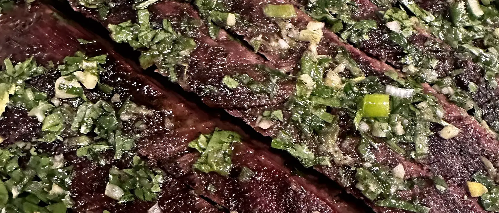 Dry-aged beef, sliced and dressed with salsa verde on a serving board