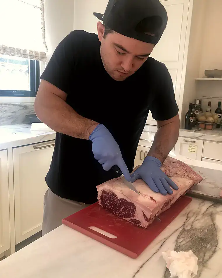 Marc breaking down a bone-in ribeye on a kitchen island